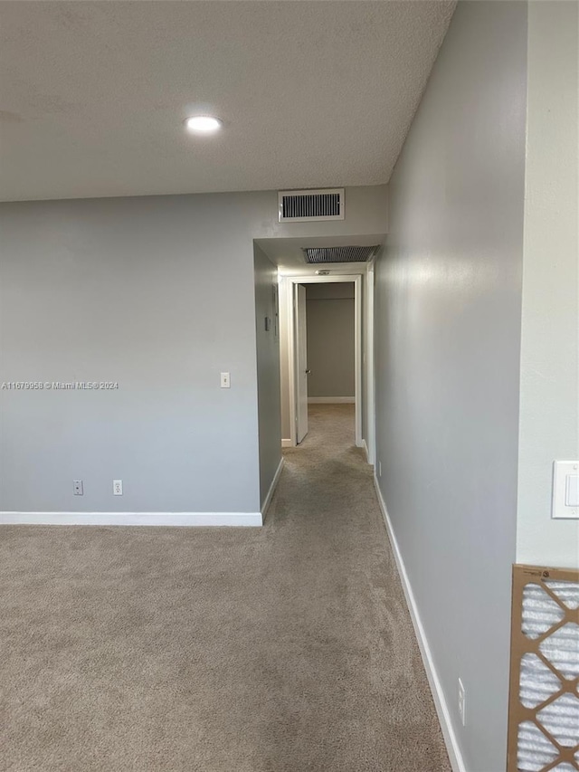 corridor with carpet floors and a textured ceiling