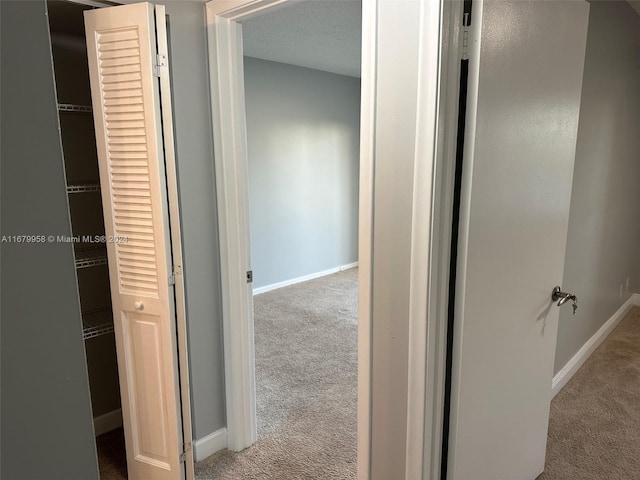 hall featuring a textured ceiling and light colored carpet