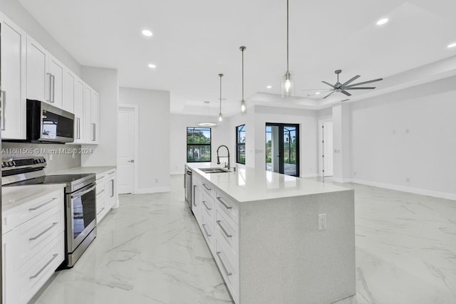 kitchen featuring appliances with stainless steel finishes, pendant lighting, white cabinetry, and an island with sink