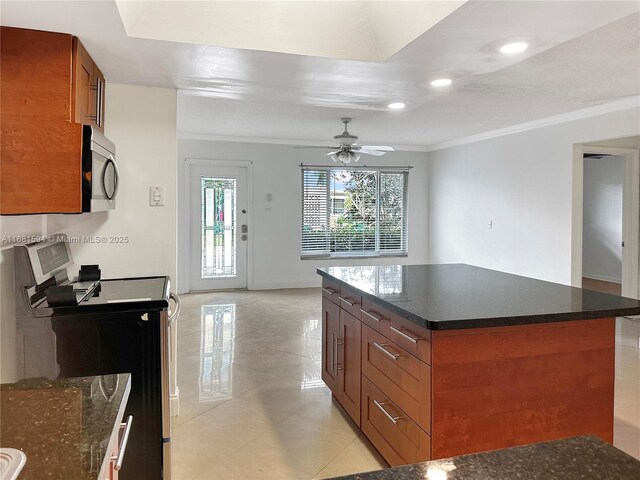 kitchen with dark stone countertops, crown molding, a center island, electric stove, and ceiling fan