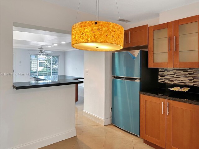 kitchen featuring backsplash, light tile patterned flooring, ceiling fan, decorative light fixtures, and stainless steel refrigerator