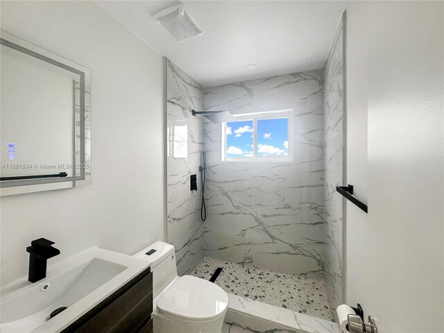 bathroom with vanity, toilet, and tiled shower