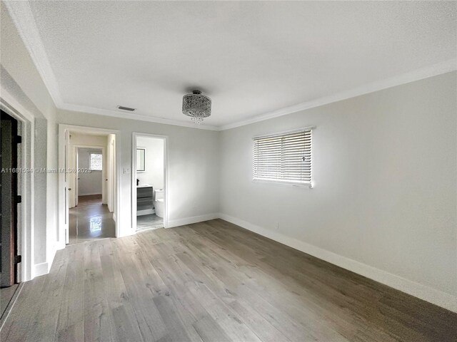 empty room featuring ornamental molding, light hardwood / wood-style flooring, and plenty of natural light