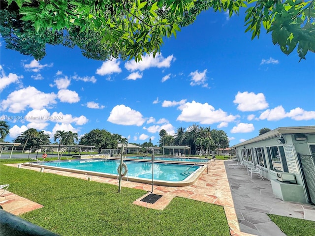 view of pool with a patio area, a lawn, and glass enclosure