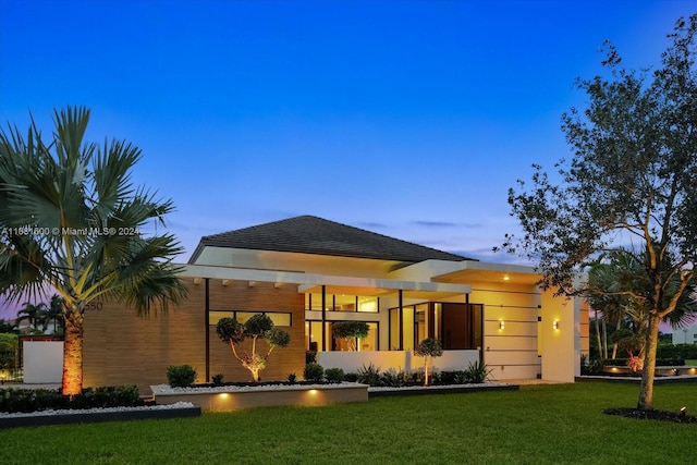 back house at dusk with a lawn