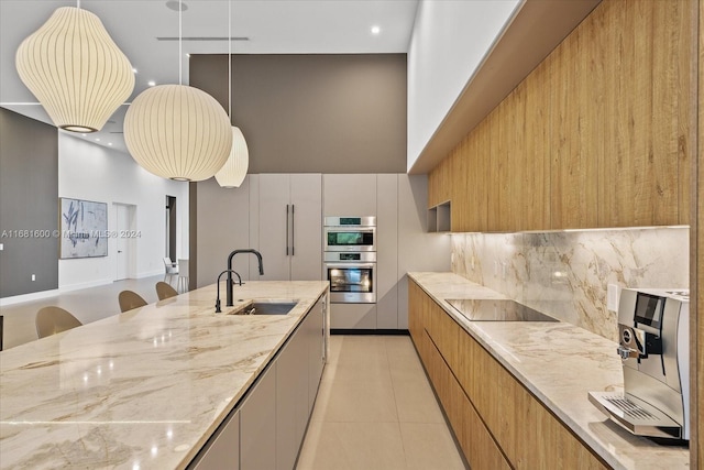 kitchen with black electric stovetop, light stone countertops, sink, double oven, and decorative backsplash