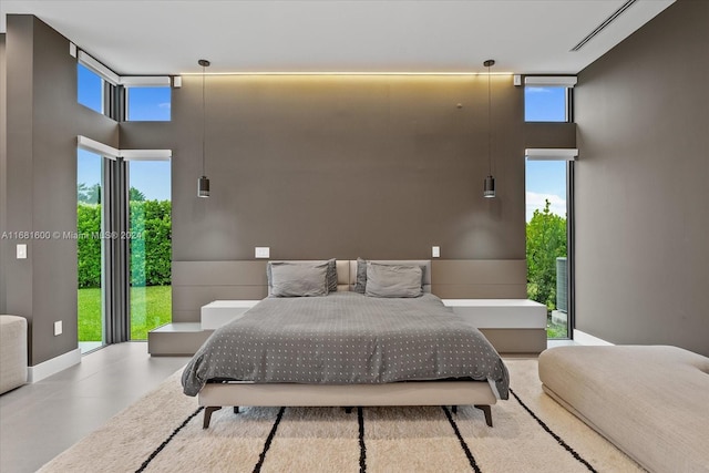 bedroom featuring concrete floors, a towering ceiling, and multiple windows