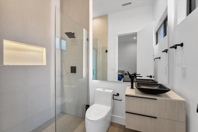 bathroom featuring vanity, toilet, and tiled shower