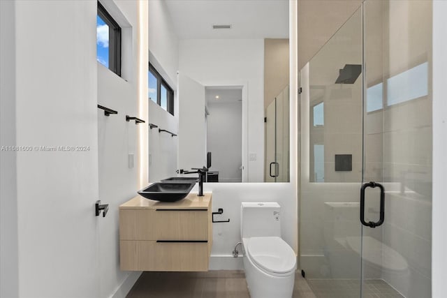 bathroom with toilet, a shower with shower door, and vanity