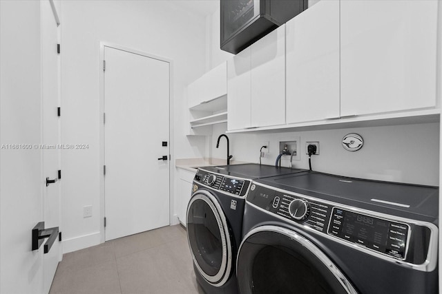 washroom with sink, light tile patterned floors, cabinets, and washing machine and clothes dryer