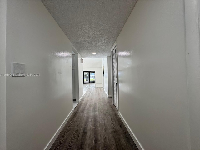 hallway featuring a textured ceiling and dark hardwood / wood-style floors