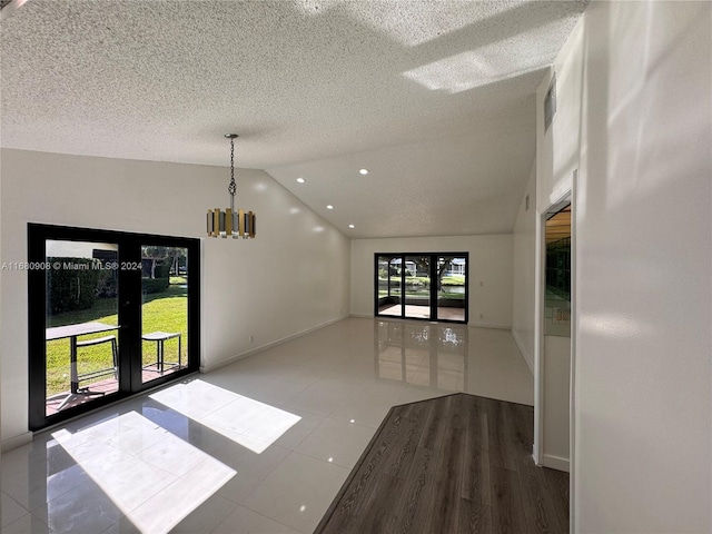 unfurnished room featuring hardwood / wood-style floors, a notable chandelier, a textured ceiling, and high vaulted ceiling