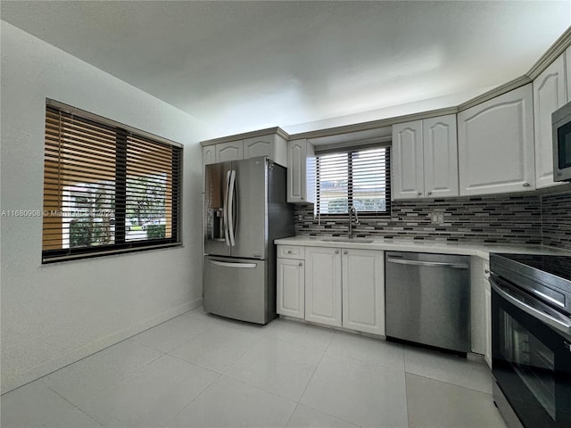 kitchen featuring appliances with stainless steel finishes, light tile patterned flooring, decorative backsplash, and sink