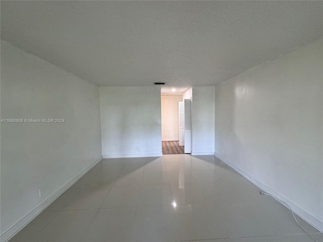 unfurnished room featuring light tile patterned flooring and a textured ceiling