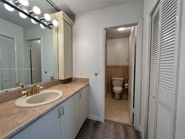 bathroom featuring vanity, toilet, wood-type flooring, and a textured ceiling