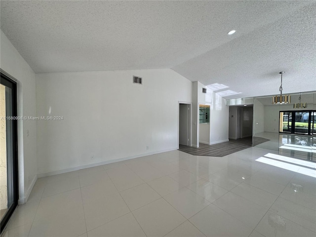 unfurnished living room with lofted ceiling, a textured ceiling, and a wealth of natural light