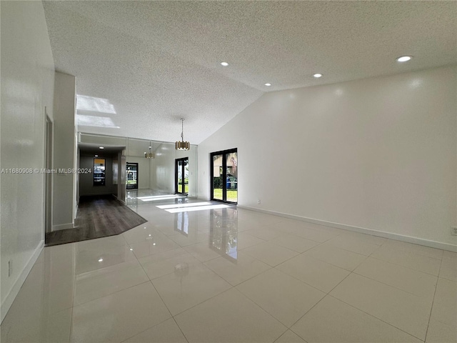 unfurnished room featuring french doors, a textured ceiling, lofted ceiling, light tile patterned floors, and an inviting chandelier