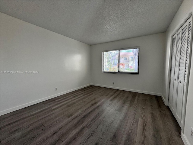 unfurnished bedroom with a closet, a textured ceiling, and dark hardwood / wood-style flooring