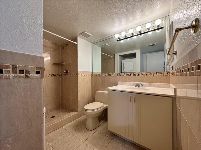 bathroom featuring a textured ceiling, tile walls, toilet, vanity, and tile patterned flooring