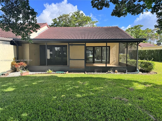 rear view of property featuring a yard and a sunroom