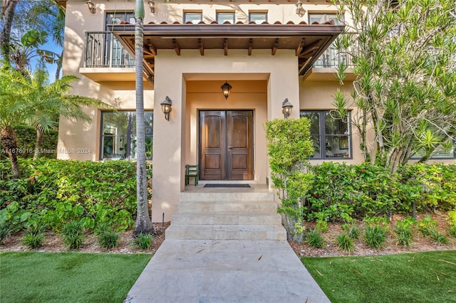 view of exterior entry featuring a yard and a balcony