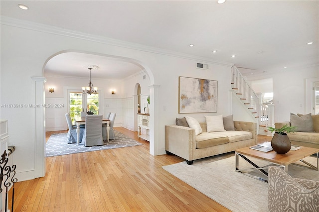 living room with an inviting chandelier, light hardwood / wood-style flooring, and crown molding