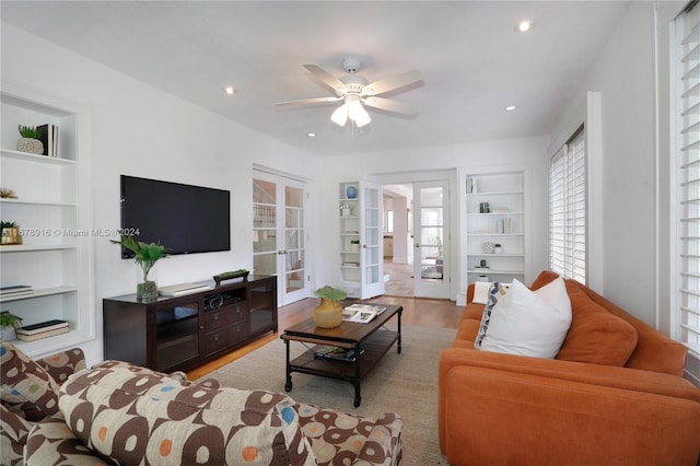 living room featuring french doors, ceiling fan, light wood-type flooring, and built in shelves