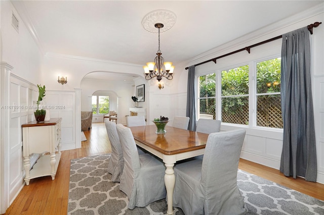 dining area with ornamental molding, a chandelier, and light wood-type flooring