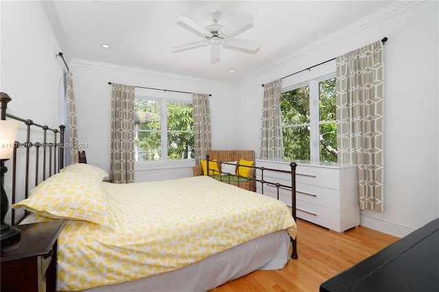 bedroom with ceiling fan, crown molding, wood-type flooring, and multiple windows