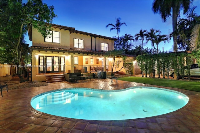 pool at dusk featuring a patio and french doors