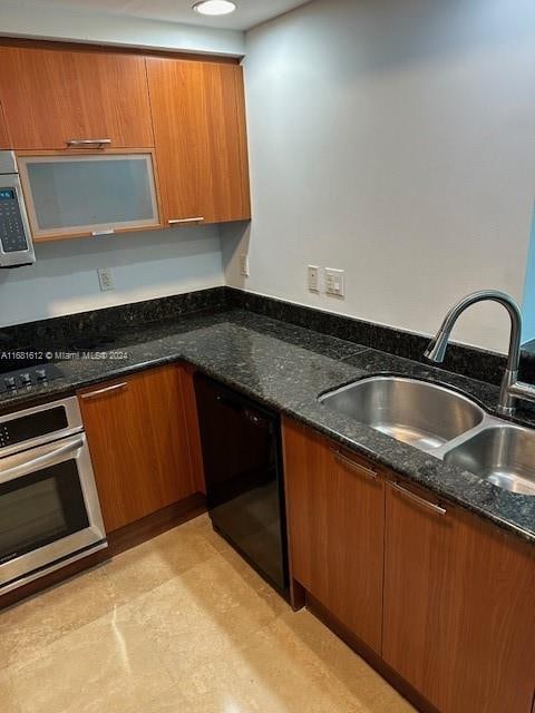 kitchen featuring black appliances, sink, and dark stone counters