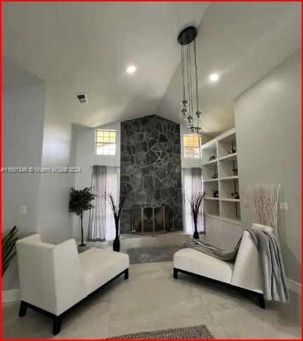 living room with vaulted ceiling and a stone fireplace