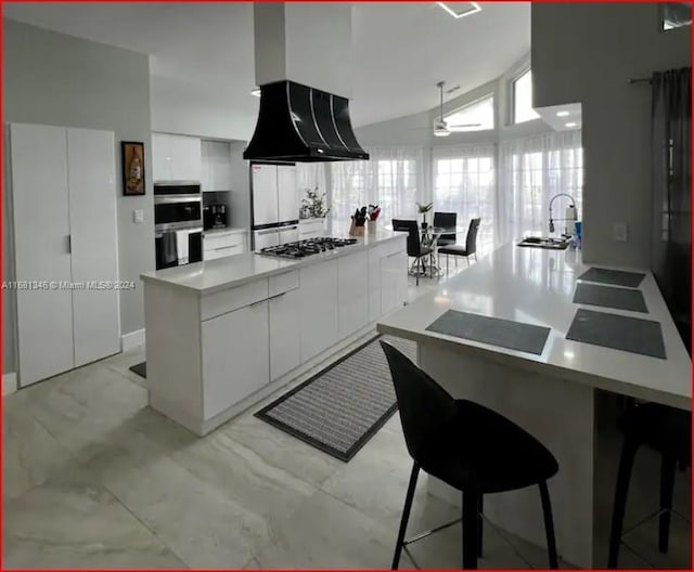 kitchen featuring lofted ceiling, kitchen peninsula, sink, white cabinets, and appliances with stainless steel finishes