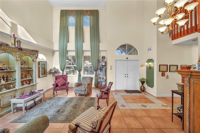 tiled entryway featuring ornamental molding, a chandelier, and a high ceiling