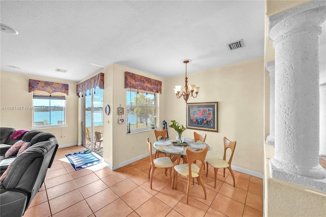 dining area with ornate columns, a water view, tile patterned floors, and a notable chandelier