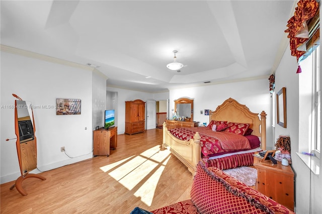 bedroom featuring multiple windows, a raised ceiling, light hardwood / wood-style flooring, and ornamental molding