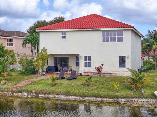 rear view of house with a yard, a water view, and a patio area