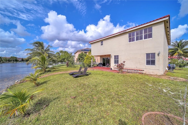 rear view of property featuring a patio, a water view, and a yard