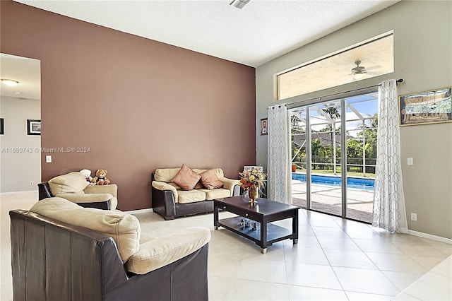 living room featuring ceiling fan, light tile patterned flooring, and a textured ceiling