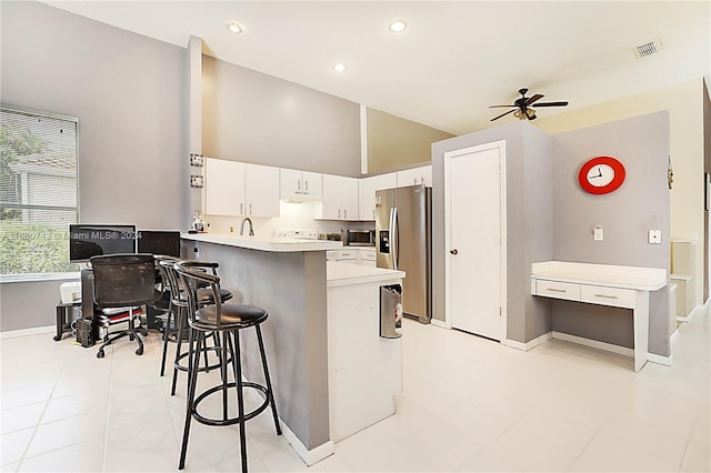 kitchen featuring kitchen peninsula, ceiling fan, a kitchen bar, white cabinetry, and stainless steel appliances