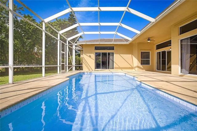 view of pool with a patio, glass enclosure, and ceiling fan