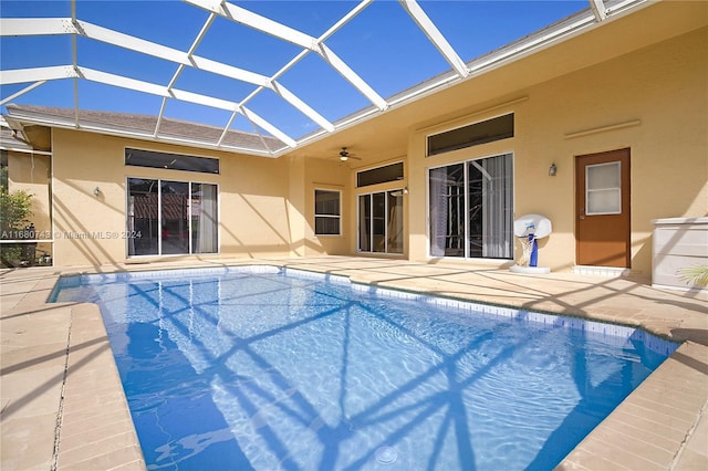 view of pool with glass enclosure, ceiling fan, and a patio