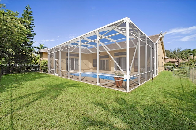 back of property featuring glass enclosure, a fenced in pool, and a yard