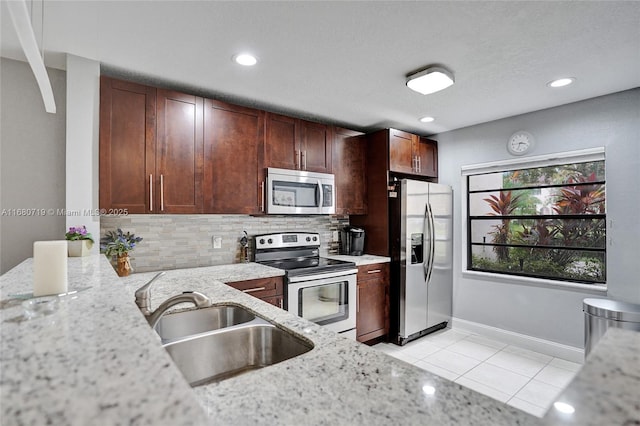 kitchen featuring sink, light tile patterned floors, tasteful backsplash, light stone counters, and stainless steel appliances