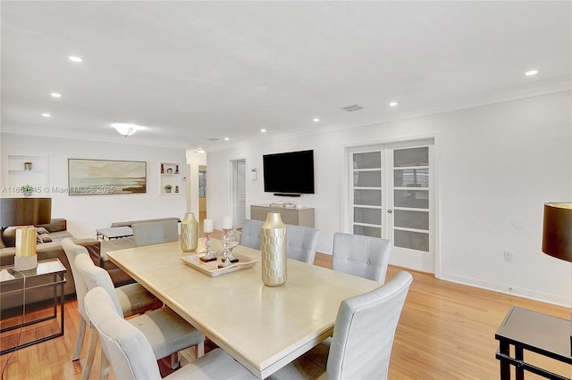 dining space with crown molding and light wood-type flooring