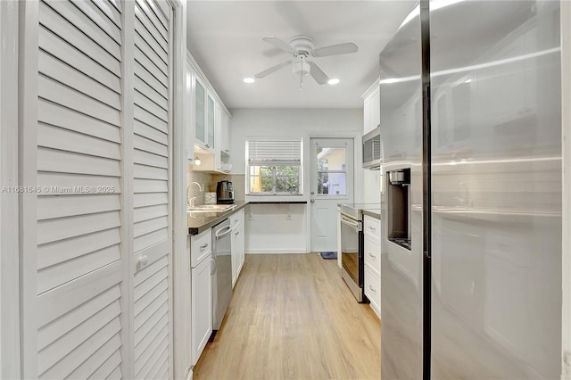 kitchen with sink, appliances with stainless steel finishes, white cabinetry, backsplash, and light wood-type flooring