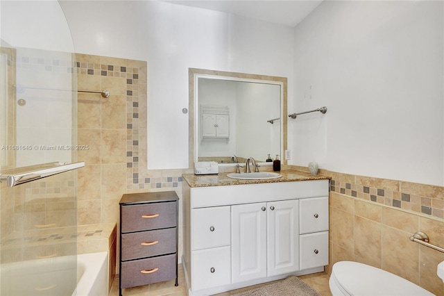 bathroom with tile patterned floors, vanity, toilet, and tile walls