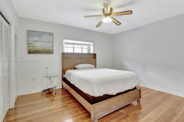 bedroom with ceiling fan, light hardwood / wood-style floors, and a closet