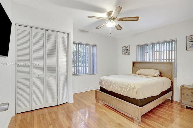 bedroom featuring multiple windows, hardwood / wood-style floors, a closet, and ceiling fan