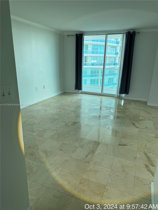 empty room featuring expansive windows and ornamental molding